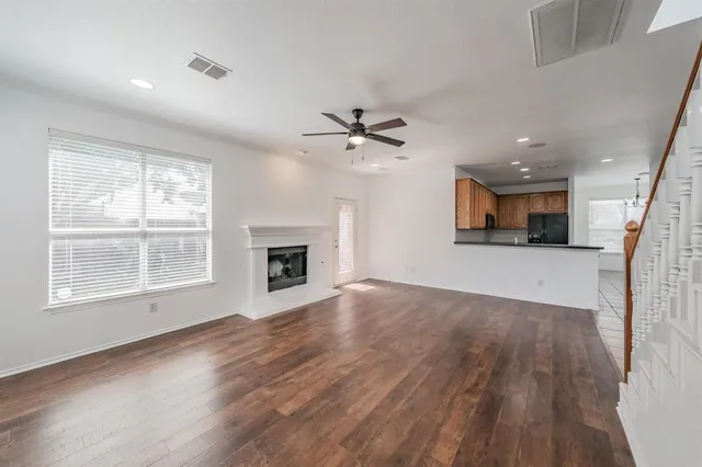 a view of a livingroom with a fireplace a ceiling fan and wooden floor