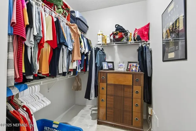 a view of walk in closet with clothes and shoes