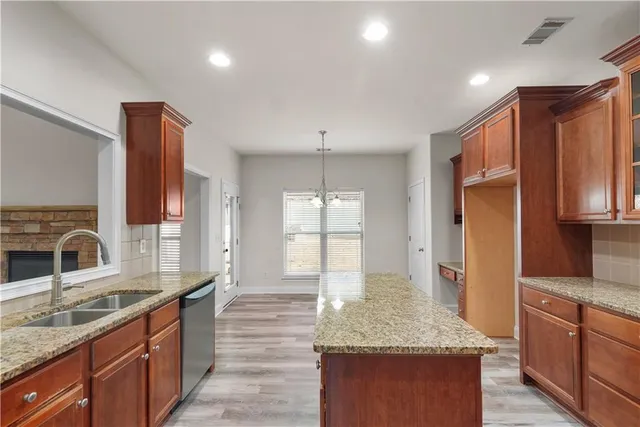 a large kitchen with granite countertop a large counter top space a sink stainless steel appliances and cabinets