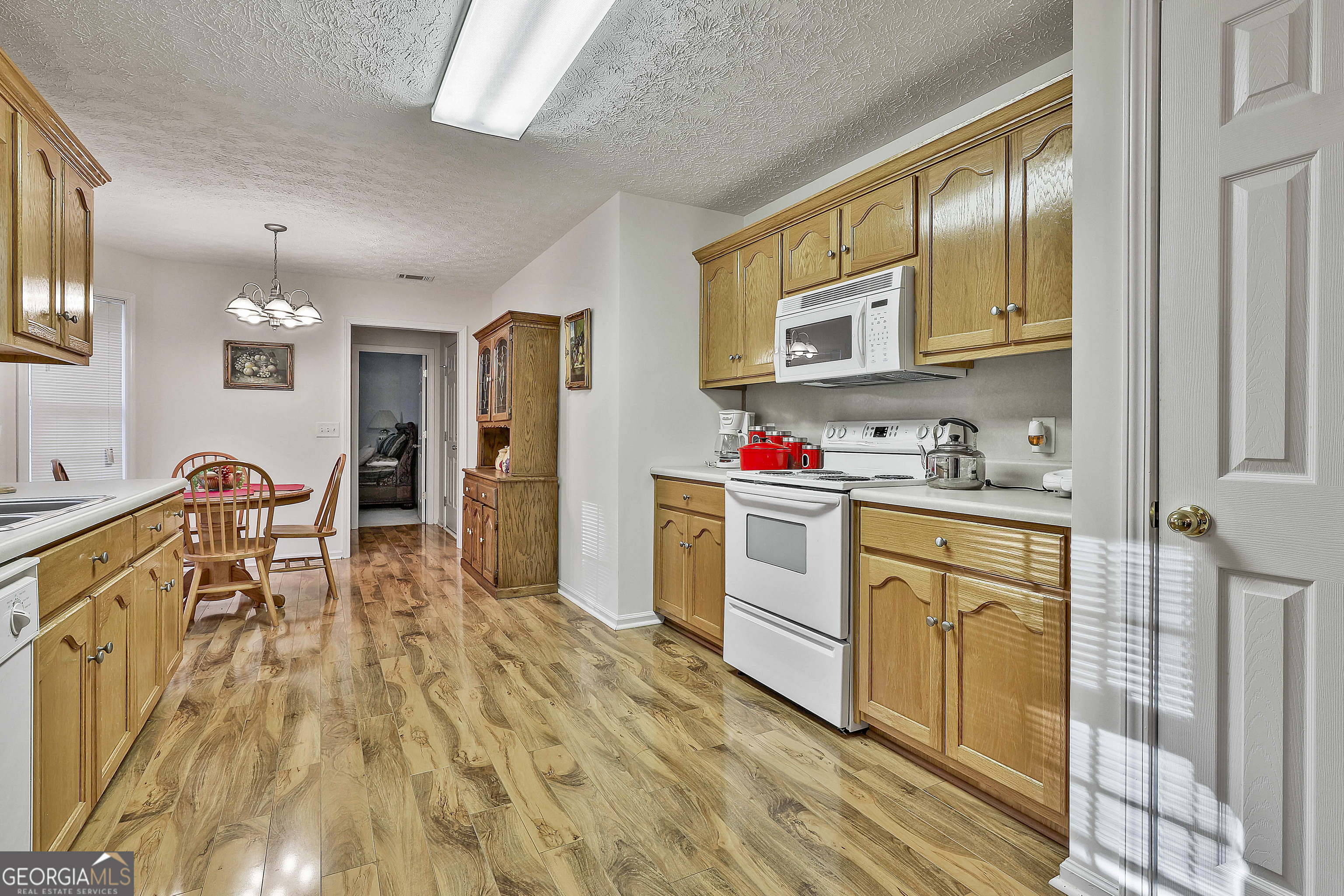 450 McKoy Road Newnan, GA 30263 - Photo 13 of 28 a kitchen with stainless steel appliances granite countertop a refrigerator a stove top oven a dining table and chairs with wooden floor