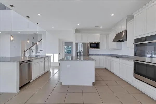 a large kitchen with stainless steel appliances granite countertop a large counter top a stove a sink and a refrigerator