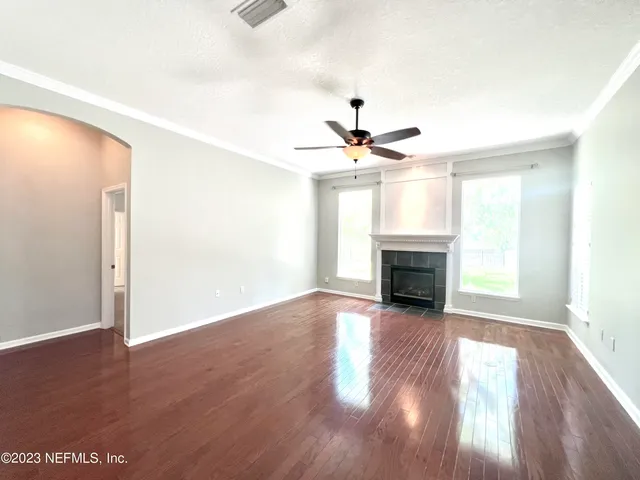 a view of a livingroom with a fireplace a ceiling fan and wooden floor