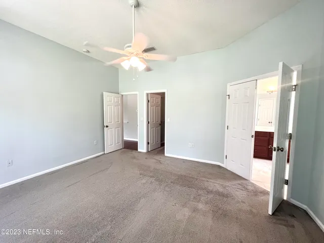 a view of a big room with a chandelier fan and windows