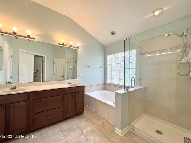 a spacious bathroom with a tub sink shower and mirror