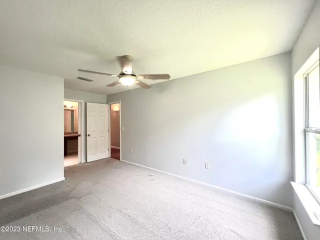 an empty room with a chandelier fan and windows
