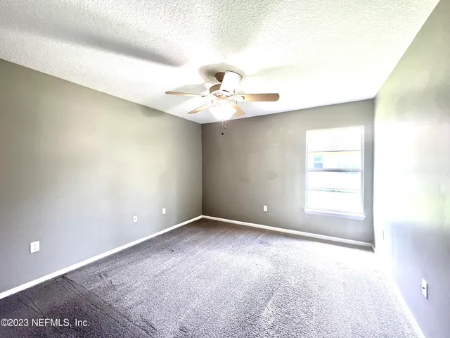an empty room with windows and chandelier fan