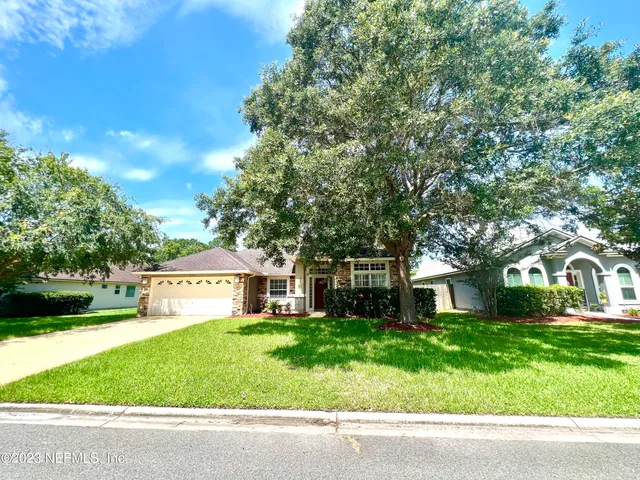 a front view of a house with garden and tree