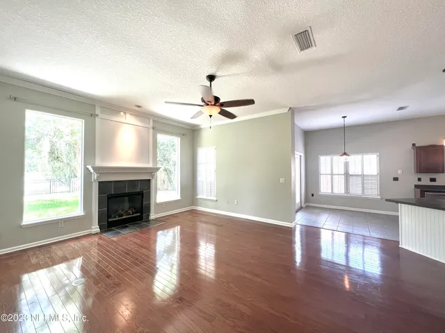 a view of an empty room with window and wooden floor