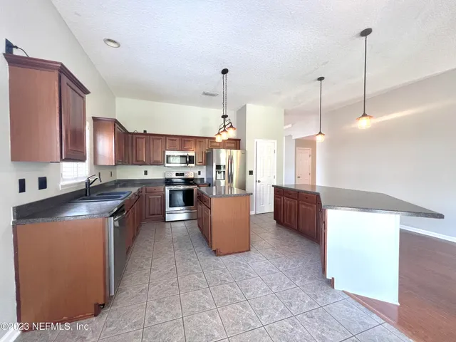 a kitchen with stainless steel appliances granite countertop a refrigerator a sink and a stove