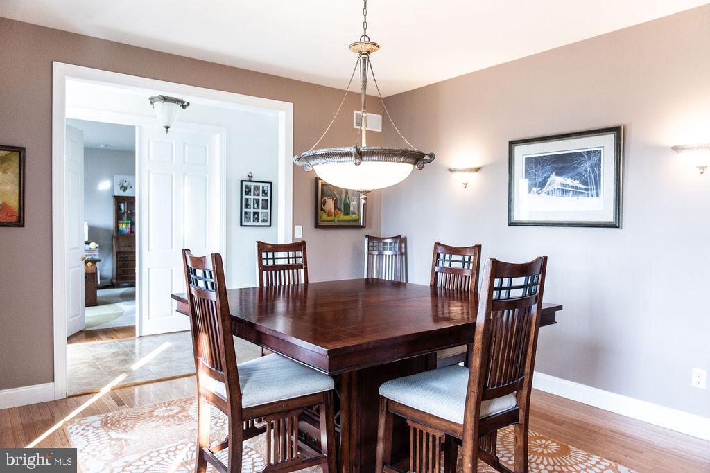 565 Sand Hill Road Hershey, PA 17033 - Photo 8 of 27 a dining room with wooden floor a chandelier a wooden table and chairs