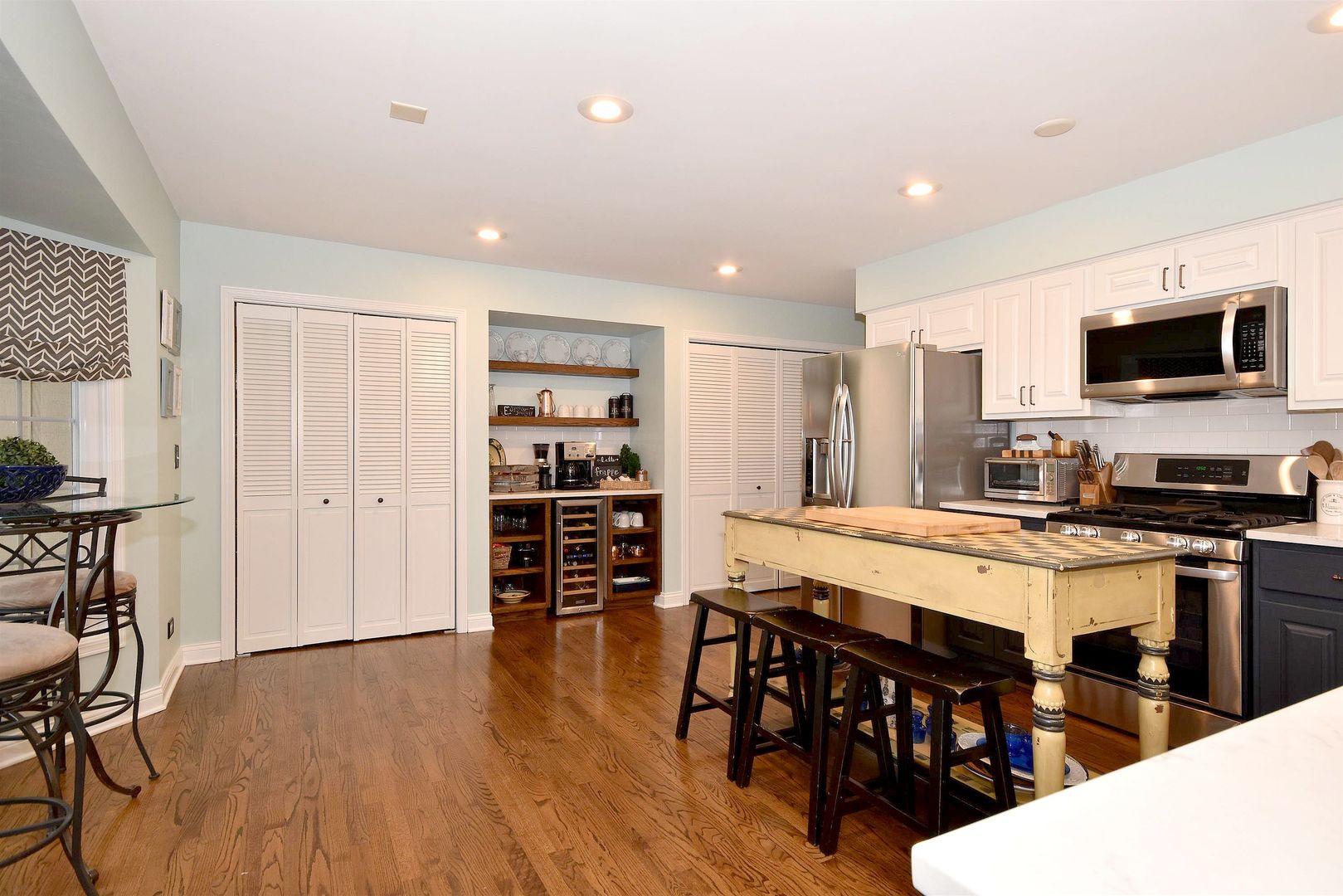 533 Lavina Drive Bolingbrook, IL 60440 - Photo 4 of 44 a large white kitchen with stainless steel appliances a stove a table and chairs with wooden floor