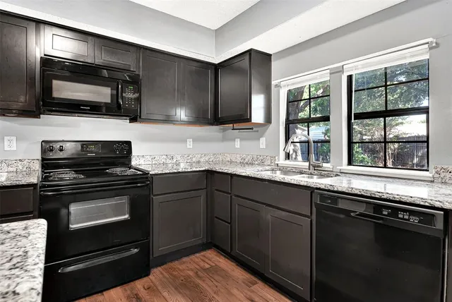 a kitchen with granite countertop a sink and steel appliances