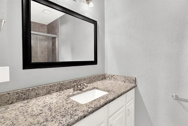 a bathroom with a granite countertop sink and a mirror