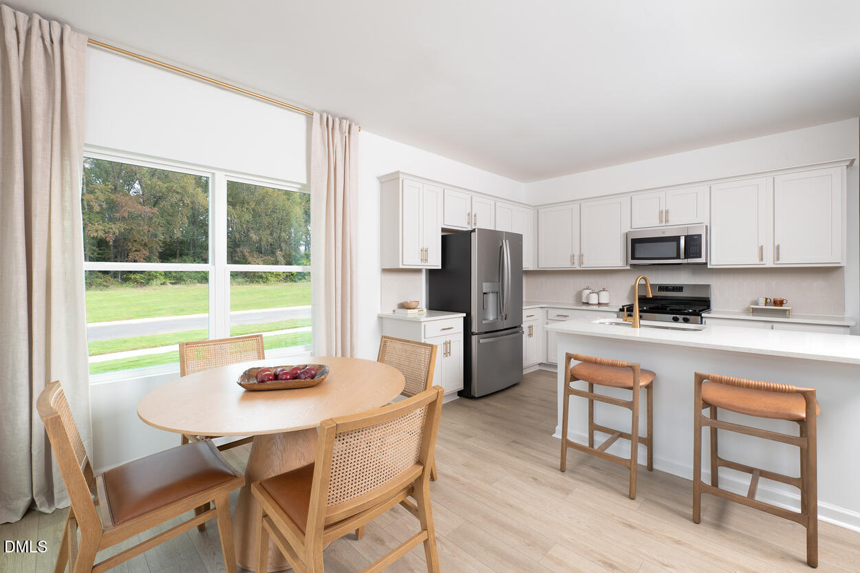 1511 Mirth Court Rolesville, NC 27571 - Photo 7 of 30 a kitchen with stainless steel appliances a dining table chairs refrigerator and microwave