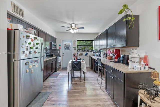 a kitchen with stainless steel appliances granite countertop a refrigerator a sink dishwasher and white cabinets with wooden floor