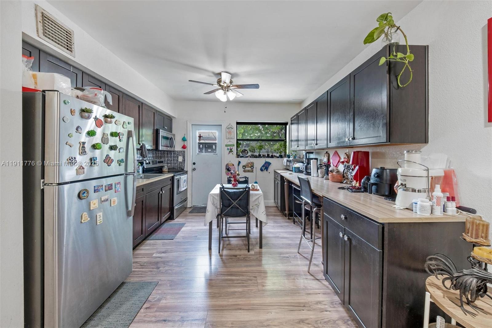 a kitchen with stainless steel appliances granite countertop a refrigerator a sink dishwasher and white cabinets with wooden floor