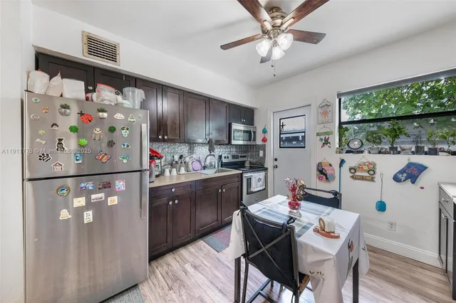 a kitchen with stainless steel appliances granite countertop a refrigerator a sink a stove a dining table and chairs with wooden floor