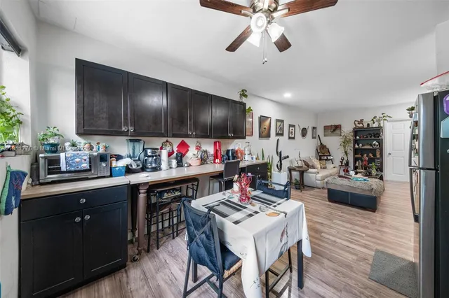 a kitchen with a dining table cabinets appliances and wooden floor
