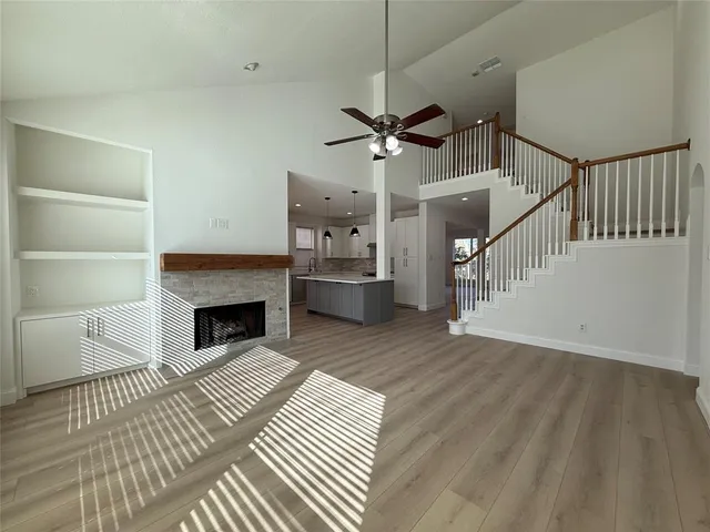 a view of a livingroom with wooden floor a ceiling fan and staircase