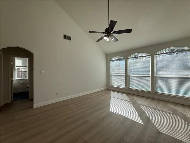 a view of an empty room with a window and wooden floor