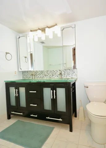 a bathroom with a granite countertop sink and a toilet