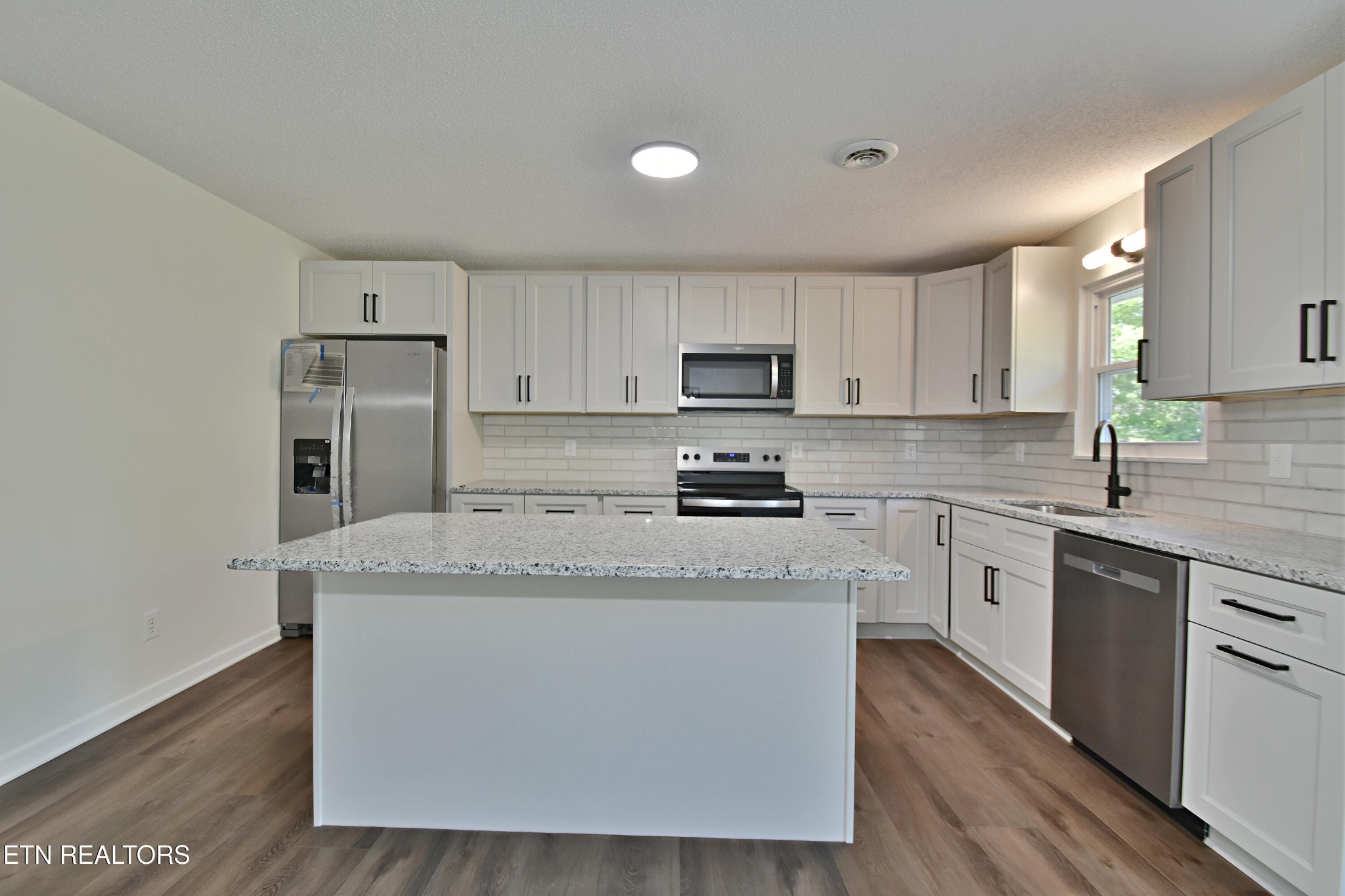 1119 Rudd Road Greenback, TN 37742 - Photo 8 of 28 a kitchen with kitchen island granite countertop a sink a stove a refrigerator cabinets and wooden floor