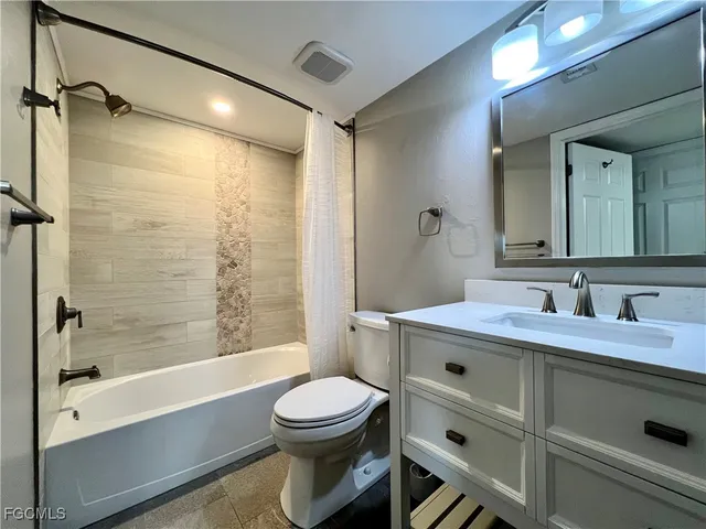 a bathroom with a bathtub shower sink vanity mirror and toilet