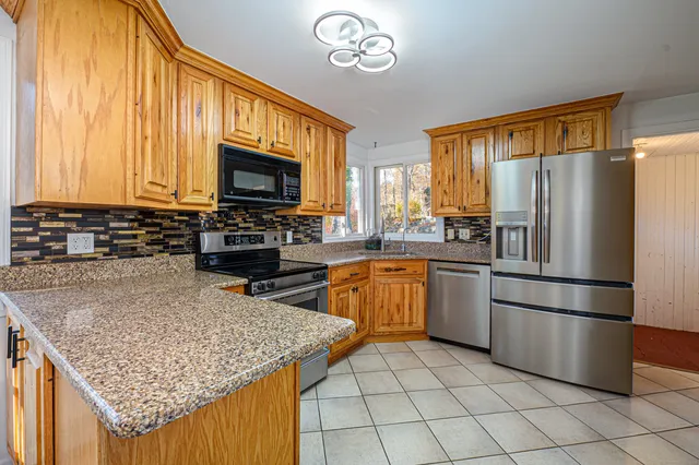 a kitchen with stainless steel appliances granite countertop a stove top oven a refrigerator a sink and dishwasher