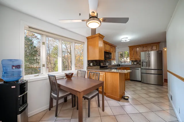 a kitchen with stainless steel appliances granite countertop a stove a refrigerator a sink dishwasher a dining table and chairs with wooden floor