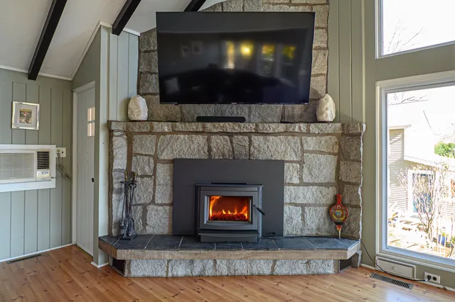 a living room with a fireplace a flat screen tv and a floor to ceiling window