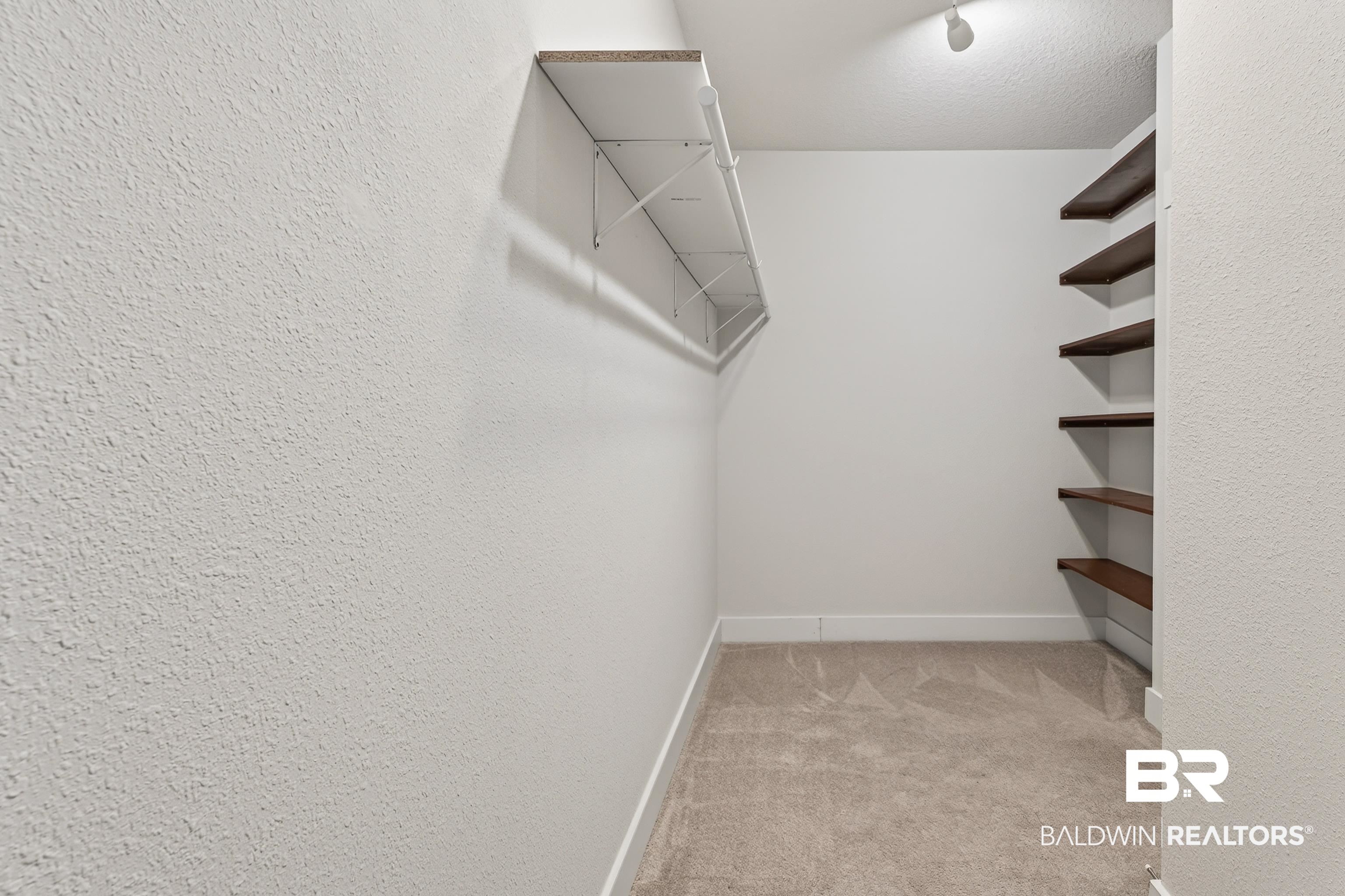 1724 Partridge Street Foley, AL 36535 - Photo 30 of 62 Walk-in closet featuring light beige carpet flooring, white baseboards, and textured walls