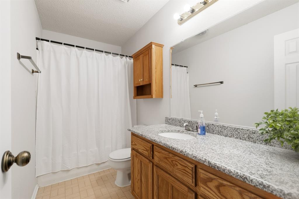 6612 Patsy Lane Watauga, TX 76148 - Photo 19 of 32 Bathroom featuring a wood vanity with a built-in sink and a light-toned speckled countertop