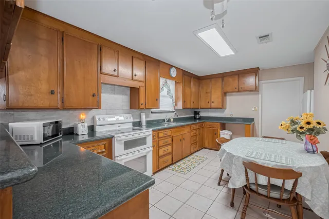 a kitchen with granite countertop a sink dishwasher a stove a refrigerator with wooden cabinets and floor