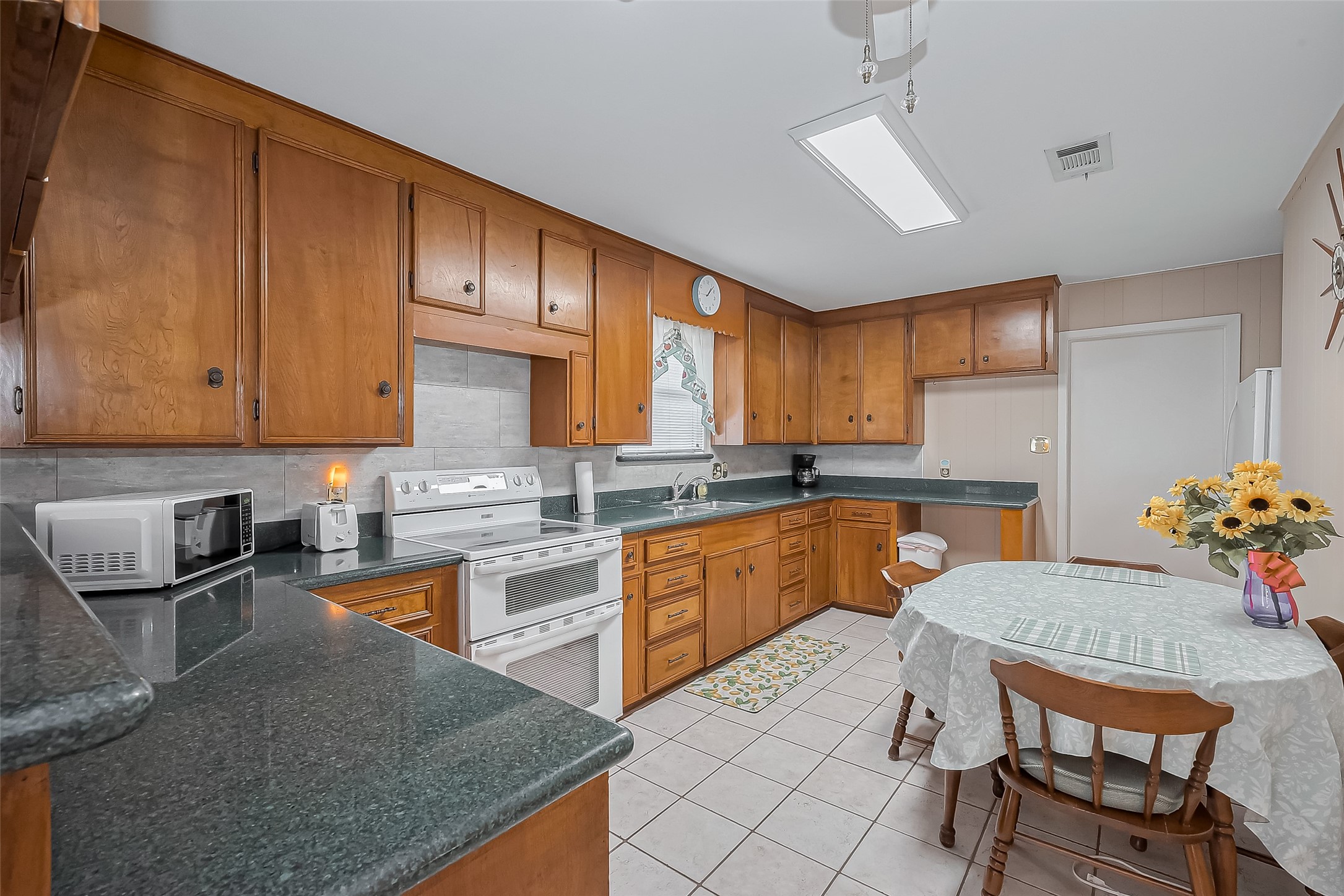 9214 Church Street Needville, TX 77461 - Photo 12 of 44 a kitchen with granite countertop a sink dishwasher a stove a refrigerator with wooden cabinets and floor