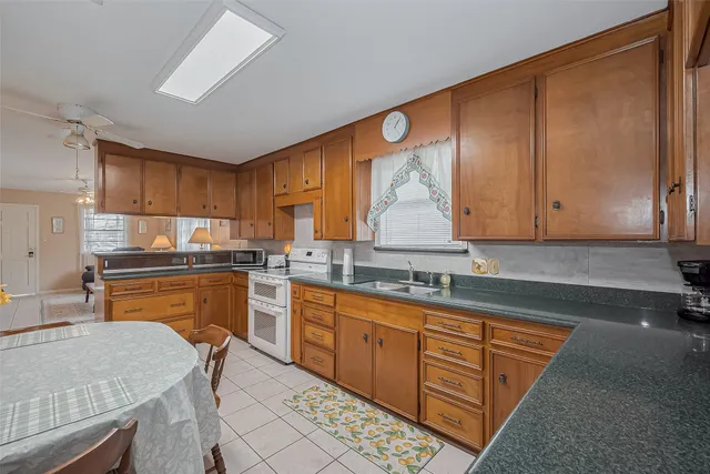 a kitchen with granite countertop wooden cabinets a sink a stove a dining table and chairs