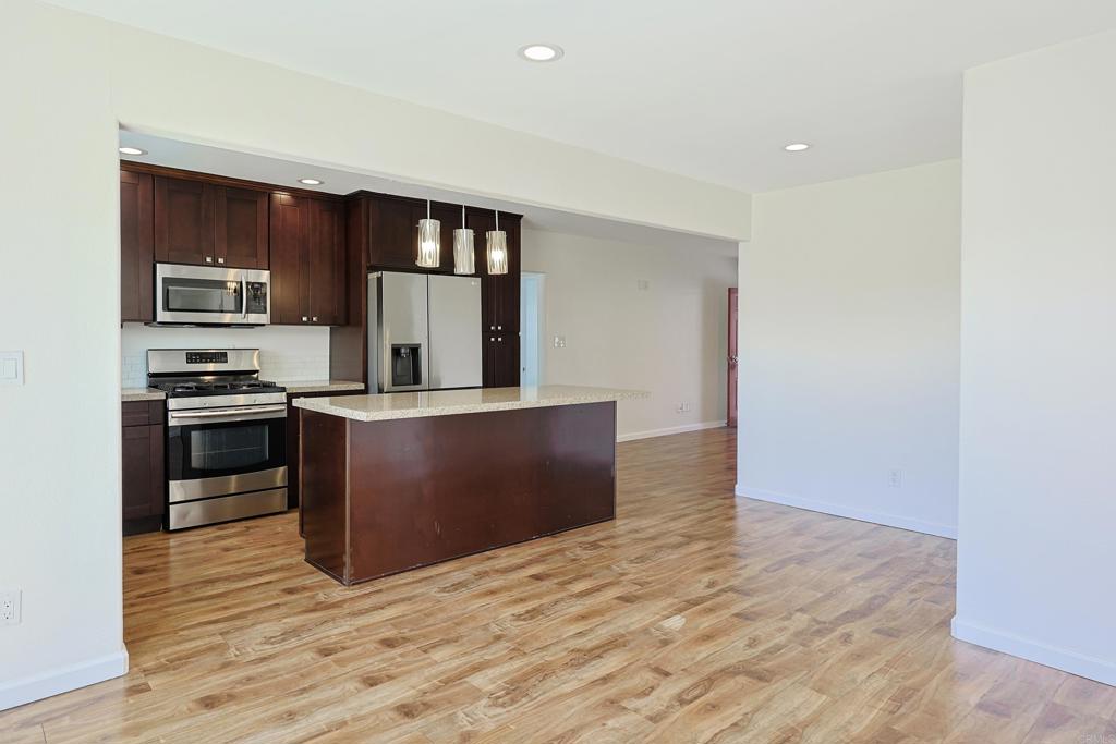 488 D Street Chula Vista, CA 91910 - Photo 8 of 25 a kitchen with stainless steel appliances kitchen island granite countertop a stove and a refrigerator