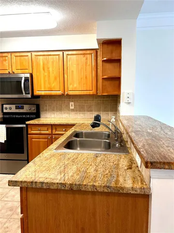 a kitchen with granite countertop a sink a counter top space and stainless steel appliances