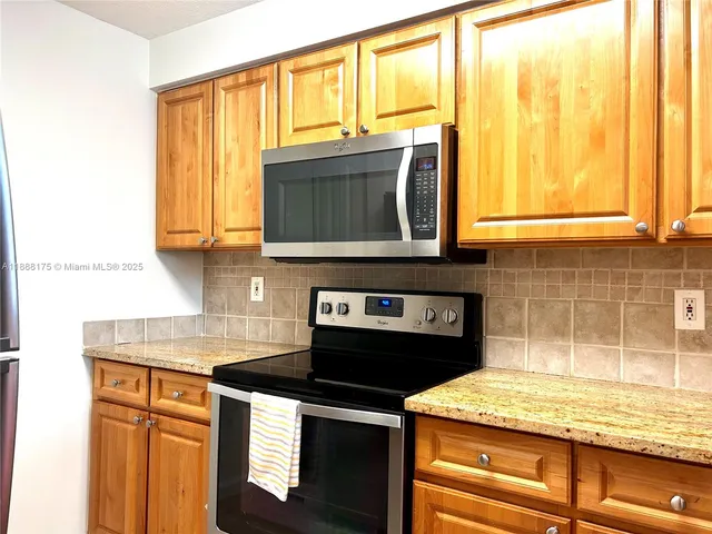 a kitchen with stainless steel appliances granite countertop a stove a sink and a microwave