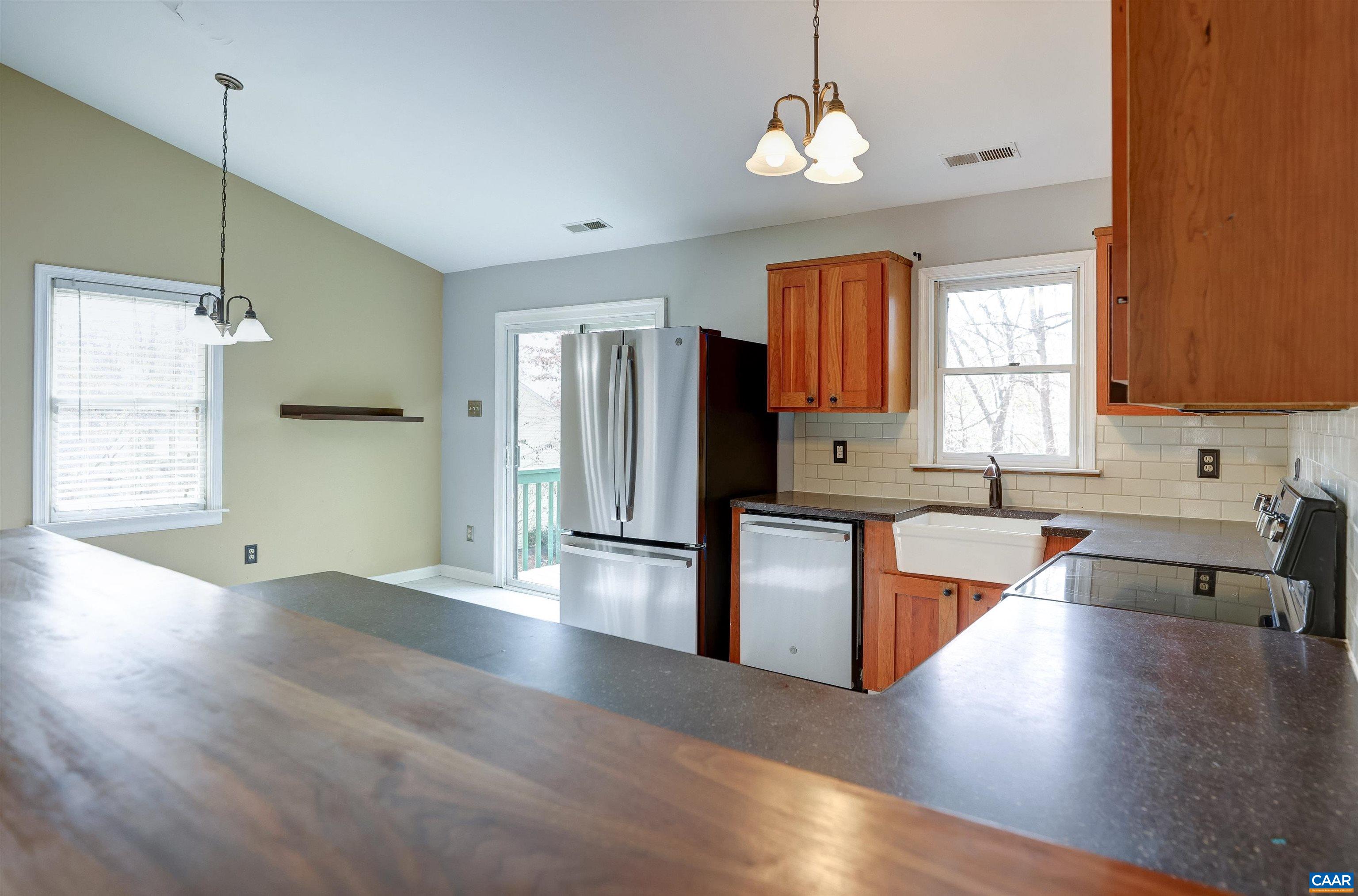1086 West Daffodil Road Ruckersville, VA 22968 - Photo 33 of 33 a large kitchen with stainless steel appliances granite countertop a refrigerator a sink dishwasher a stove and white countertops with wooden floor