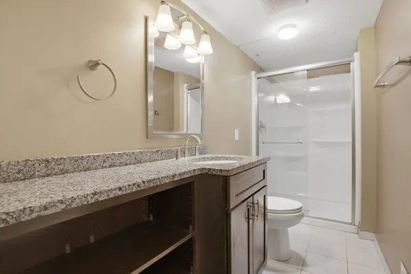 a bathroom with a granite countertop sink a toilet and a mirror
