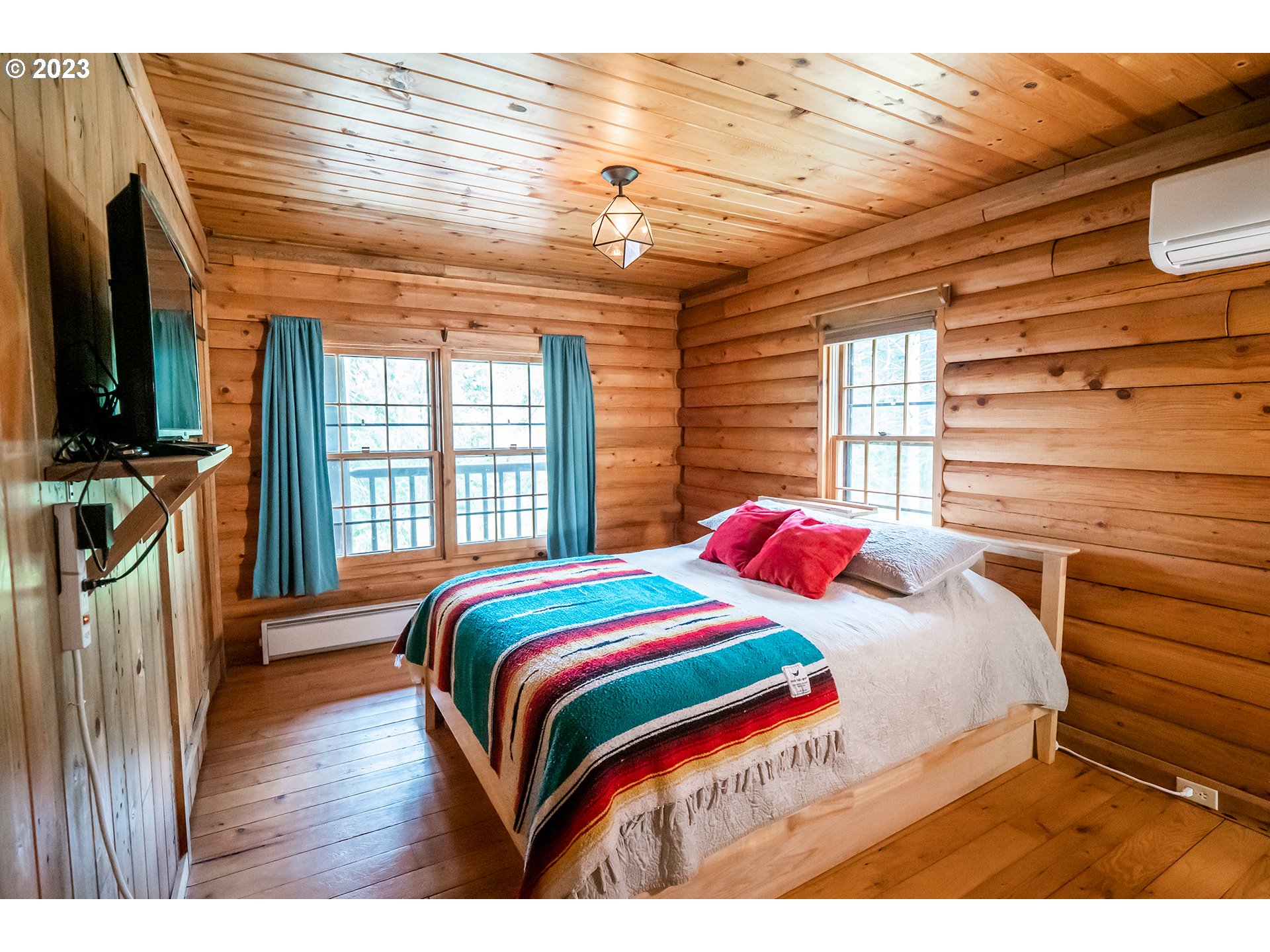29588 Simmons Road Eugene, OR 97405 - Photo 14 of 44 a bedroom with a bed a flat screen tv and a large window with wooden floor
