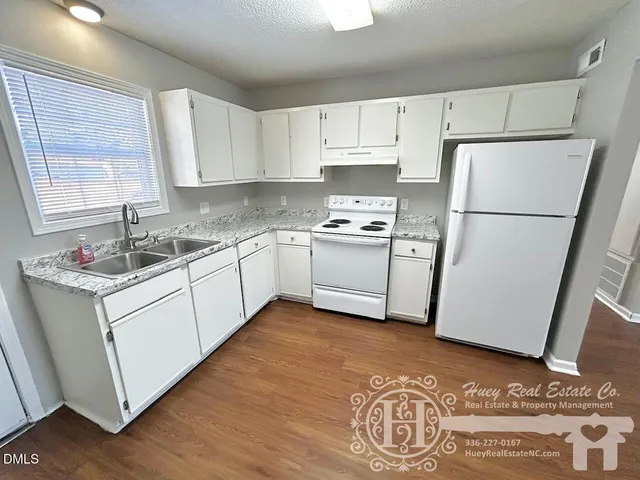 a kitchen with a sink a refrigerator and white cabinets