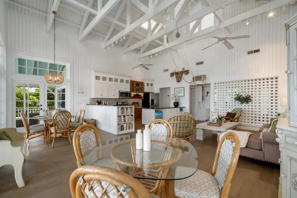 a dining room with wooden floor a chandelier a glass table and chairs