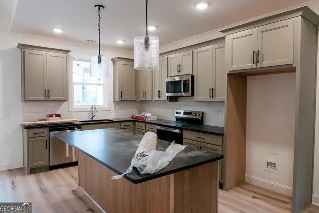 a kitchen with kitchen island granite countertop a sink a counter space appliances and cabinets