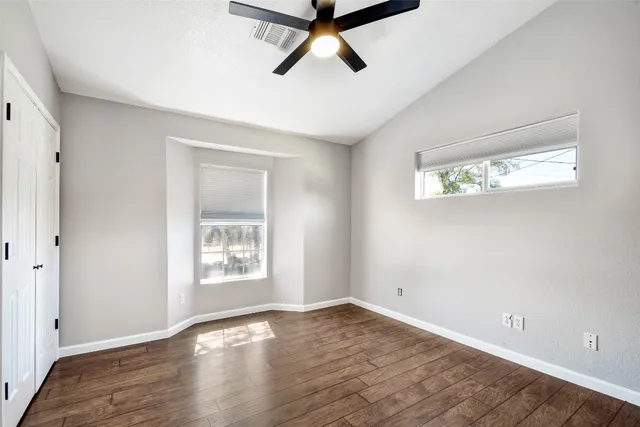 a view of empty room with wooden floor and fan