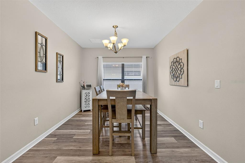 11214 Carrick Stone Street Wimauma, FL 33598 - Photo 14 of 73 a view of a dining room with furniture and wooden floor