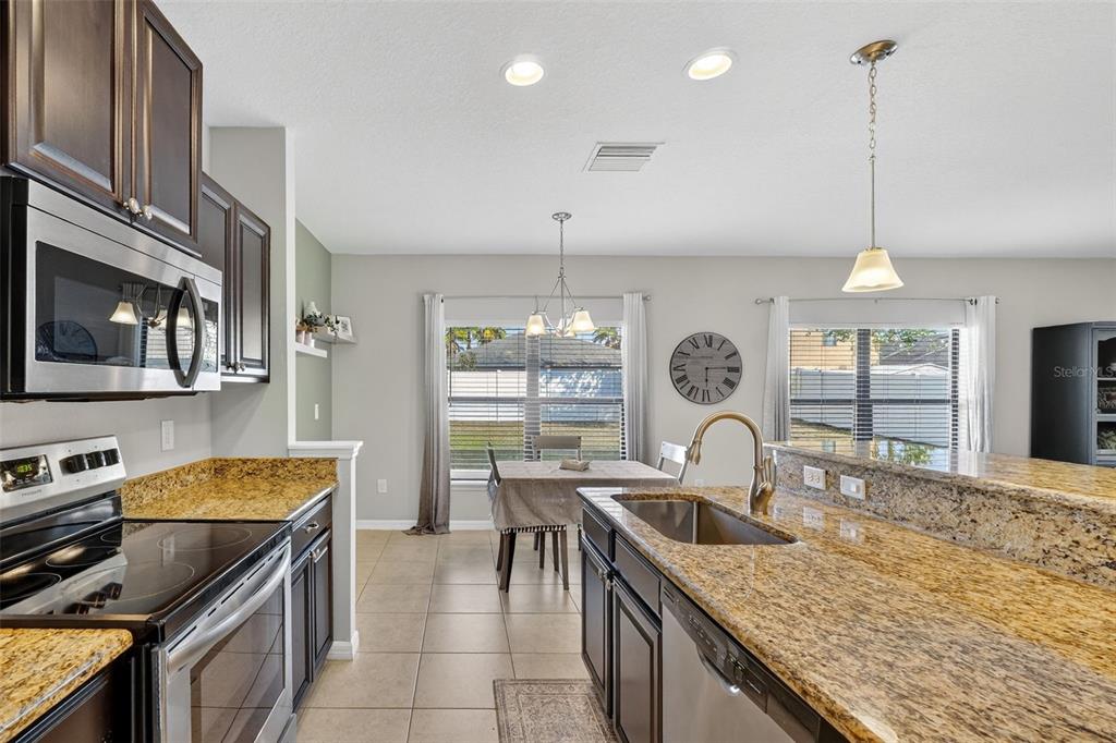11214 Carrick Stone Street Wimauma, FL 33598 - Photo 20 of 73 a kitchen with stainless steel appliances granite countertop a sink a stove and a wooden floors