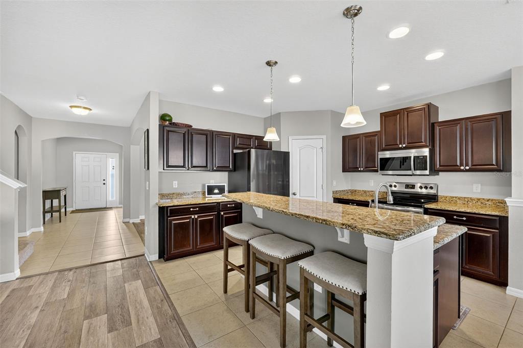 11214 Carrick Stone Street Wimauma, FL 33598 - Photo 21 of 73 a kitchen with stainless steel appliances granite countertop a stove top oven a sink dishwasher a refrigerator and white cabinets with wooden floor