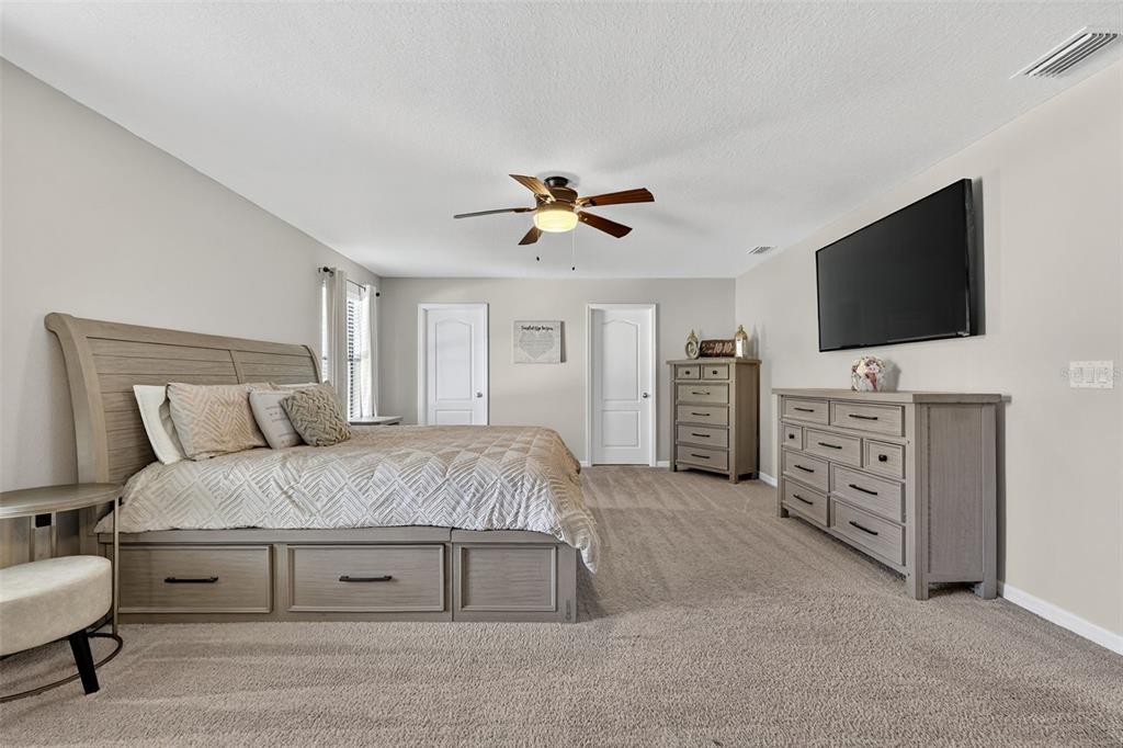 11214 Carrick Stone Street Wimauma, FL 33598 - Photo 35 of 73 a spacious bedroom with a bed and a flat screen tv