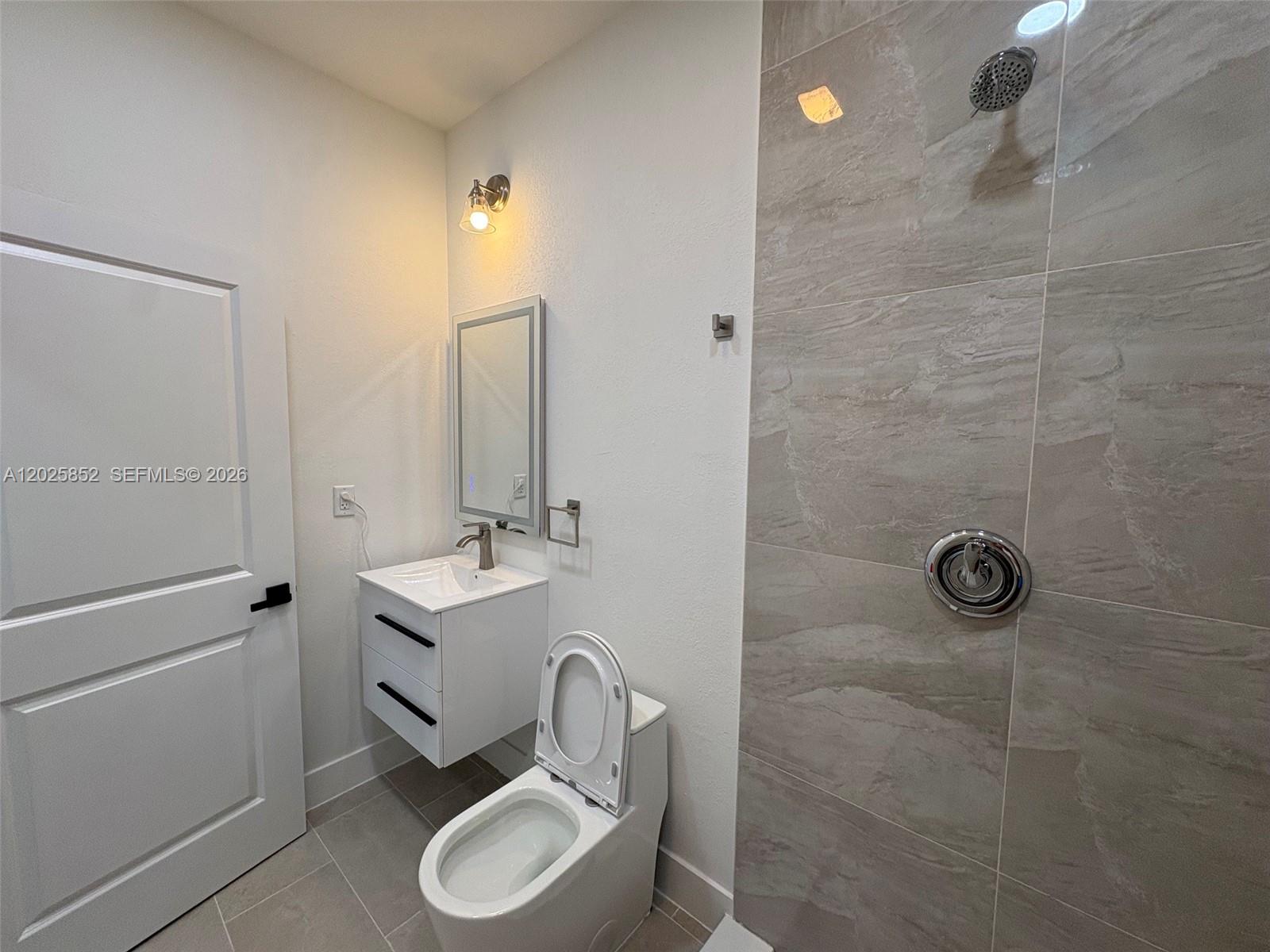 12948 Southwest 265th Terrace, Unit STUDIO Homestead, FL 33032 - Photo 15 of 16 a bathroom with a granite countertop sink toilet a mirror and vanity